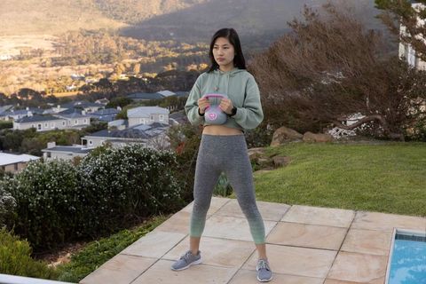 Woman exercising with kettlebell outdoors overlooking scenic view