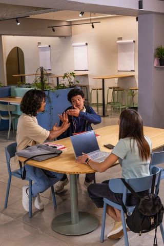 Multicultural students collaborating and debating project at modern study lounge round table