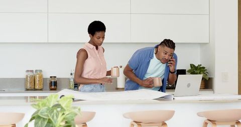 Diverse Couple Reviewing Blueprints in Modern Kitchen