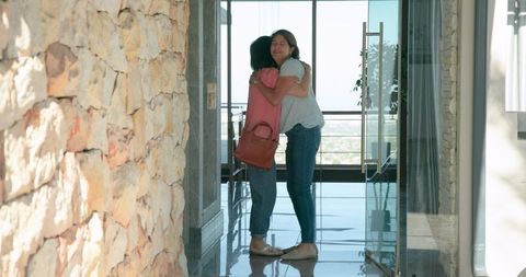 Senior friends enjoying warm reunion hug at home entrance