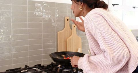 Woman cooking indian cuisine in modern kitchen setting