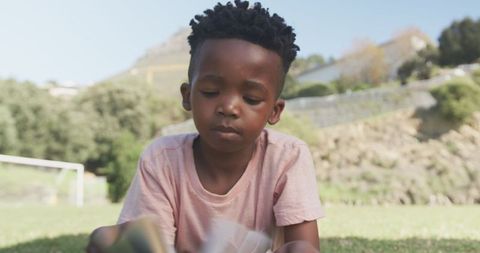 Young boy enjoying outdoor reading on sunny day
