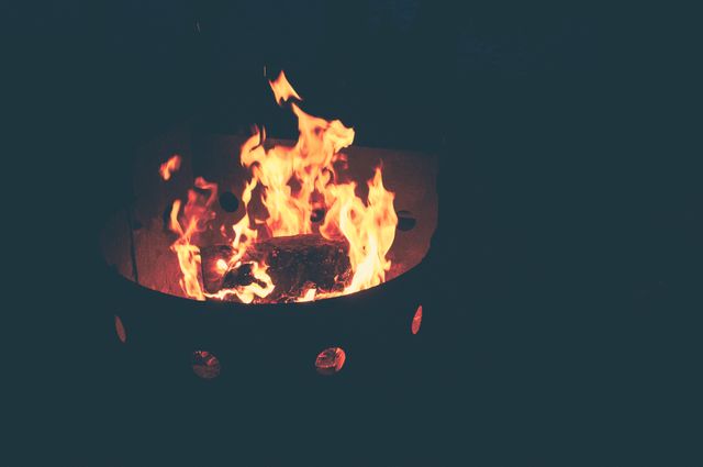 Image showcases a campfire with bright flames in an outdoor nighttime setting. It is ideal for depicting camping, outdoor activities, warmth, and nighttime coziness. This visual is perfect for promoting outdoor gear, camping accessories, adventure blogs, or creating motivational and inspirational content related to nature and wilderness.