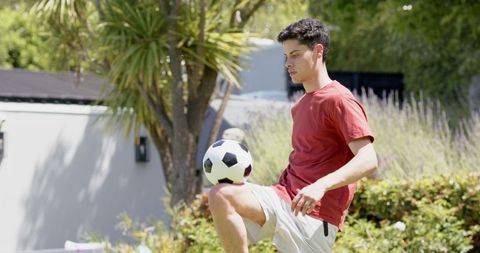 Young Man Practicing Soccer Skills in Lush Garden Setting