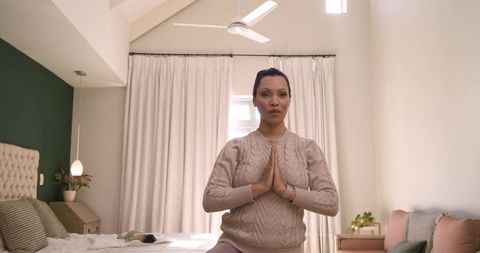 Mother engaging in mindful prayer with baby in calm bedroom setting