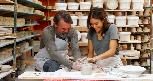 Two People Collaborating on Pottery in Studio with Shelves of Finished Work - Download Free Stock Images Pikwizard.com