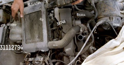 Mechanic inspecting grimy engine block with corrugated intake hose and white cloth