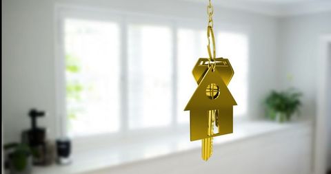 Golden house keychain hanging in bright minimalist kitchen