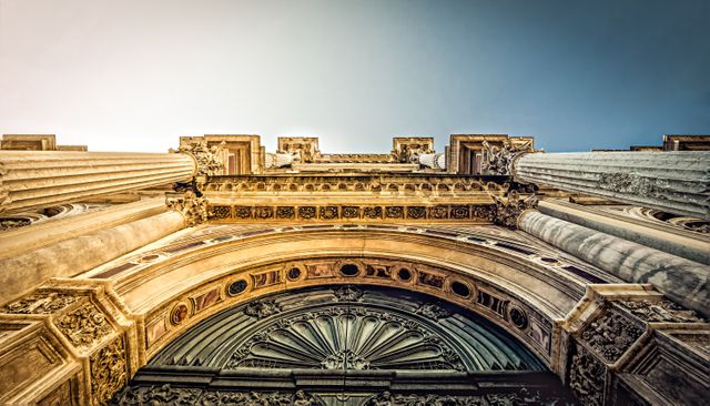Low angle view of an ornate Gothic architectural structure with columns and detailed decorations on the facade. Suitable for use in travel brochures, architectural studies, historical documentation, and educational materials about European heritage.