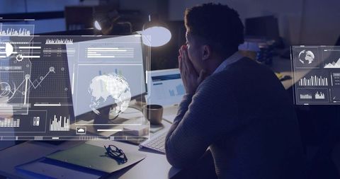 Midnight analyst studying interactive data dashboards and HUD overlays on office monitors