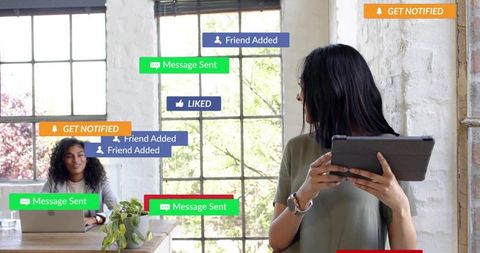 Woman Checking Tablet While Colleague Working on Laptop with Floating Social Alerts in Loft