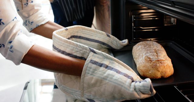 Freshly Baked Bread Being Taken Out of Oven by Person Wearing Oven Mitts - Download Free Stock Images Pikwizard.com