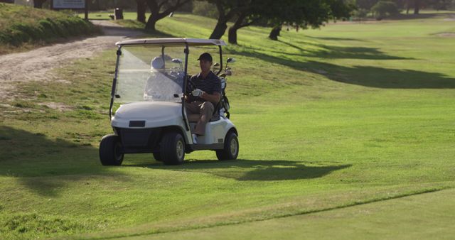 Happy caucasian male golf players riding golf cart at golf course. Golf, sport and active lifestyle, unaltered.
