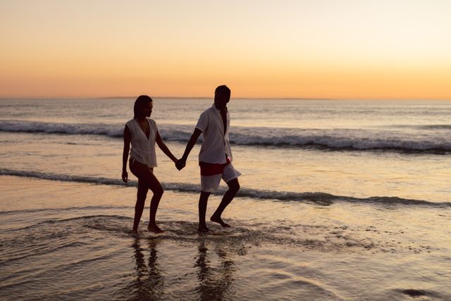 Young couple walking hand in hand on the beach