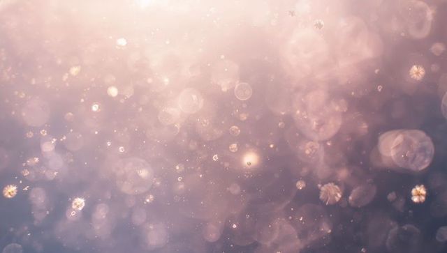 Ethereal mauve bokeh with floating luminous particles, crystal highlights and dreamy pastel glow