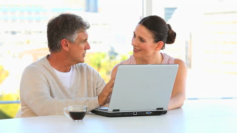 Couple Collaborating on Laptop Over Coffee in Bright Office