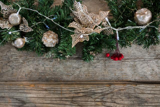 Christmas tree decorations including glittery ornaments, pine cones, and red berries on a rustic wooden background. Ideal for holiday greeting cards, festive advertisements, and seasonal blog posts.