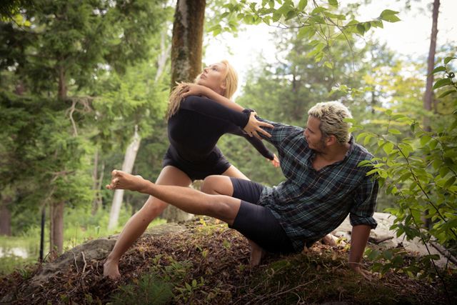Couple engaged in a yoga pose amidst a lush forest, showcasing flexibility and balance. Ideal for illustrating themes of healthy lifestyle, outdoor fitness, nature retreats, yoga practice, and couples activities.