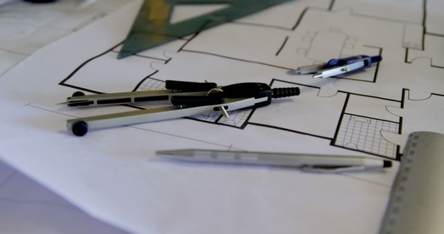 Architect's tools rest on a blueprint in an office. Precision instruments like compasses and rulers are essential for drafting plans.