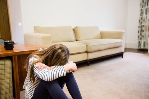 Young Girl Sitting on Carpet Hugging Knees