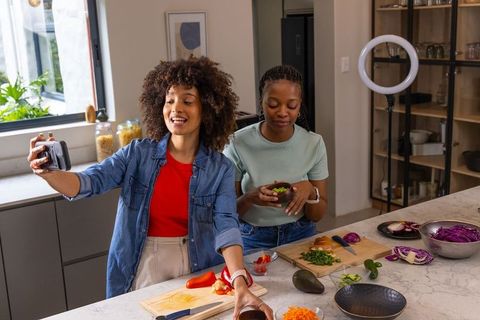 African American Friends Filming Cooking Vlog Together in Bright Modern Kitchen
