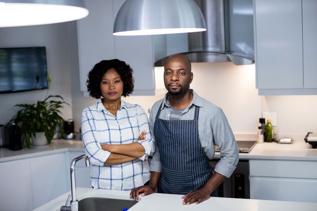 Couple standing confidently in a modern kitchen, showcasing a strong partnership and teamwork. Ideal for use in lifestyle blogs, home improvement articles, and advertisements related to kitchen appliances or home decor.