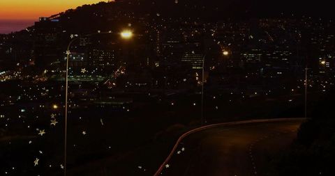 Curving asphalt road with city lights at dusk