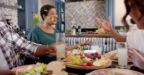 Friends gathering around kitchen table sharing charcuterie board, laughter and drinks