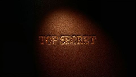 Embossing gold top secret on dark leather cover with dramatic spotlight and deep shadow