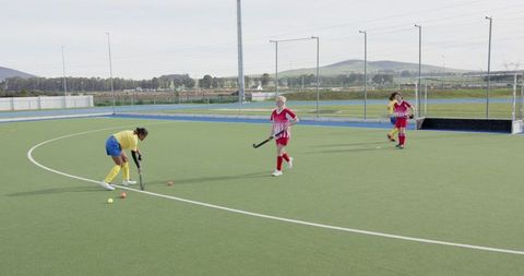 Teenagers Engaged in Dynamic Field Hockey Match on Turf Field