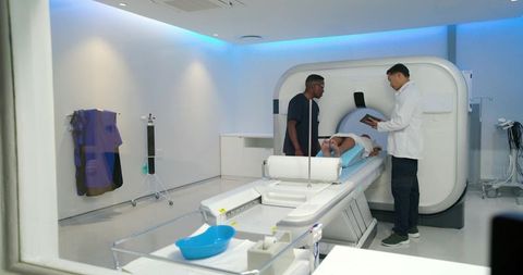 Radiology team assisting patient entering ct scanner in modern bright imaging suite