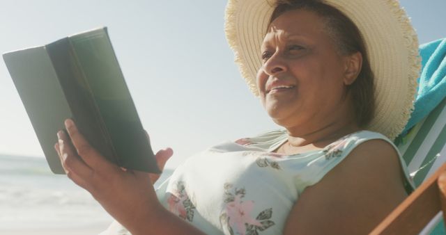 Smiling Senior Woman Reading Book on Beach in Sunshine - Download Free Stock Images Pikwizard.com