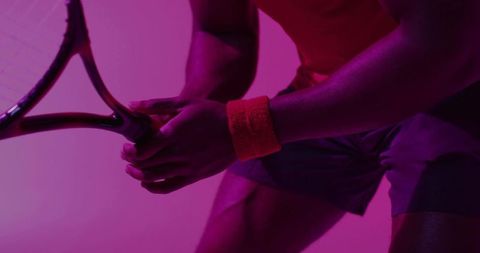 Magenta tennis closeup gripping racket with orange wristband athletic power motion