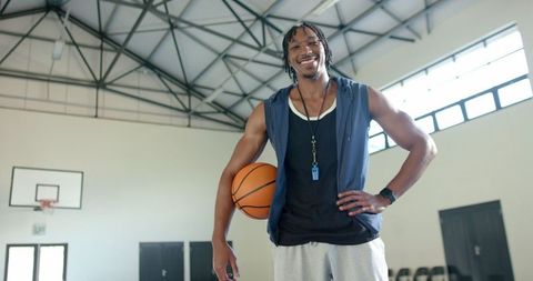 Motivational basketball coach standing confidently holding basketball