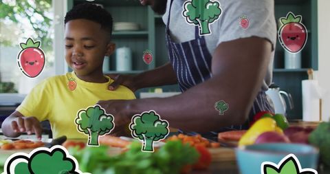 Father and son cooking together surrounded by floating vegetables