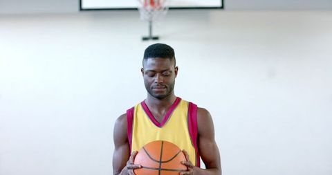 Focused Athlete Holding Basketball on Court in Concentration