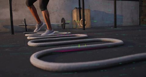 Woman performing dynamic fitness routine with battle ropes
