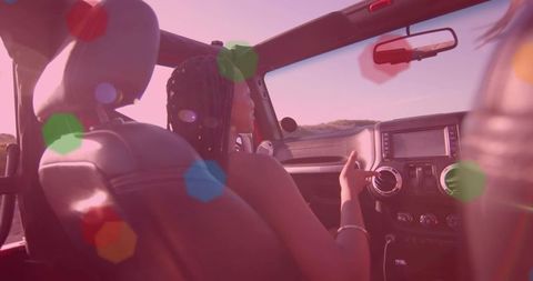 Woman driving convertible on scenic coastal highway at sunset