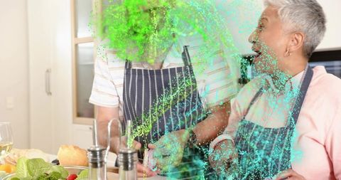 Mature couple chopping fresh salad amid vibrant green particle overlay, home cooking