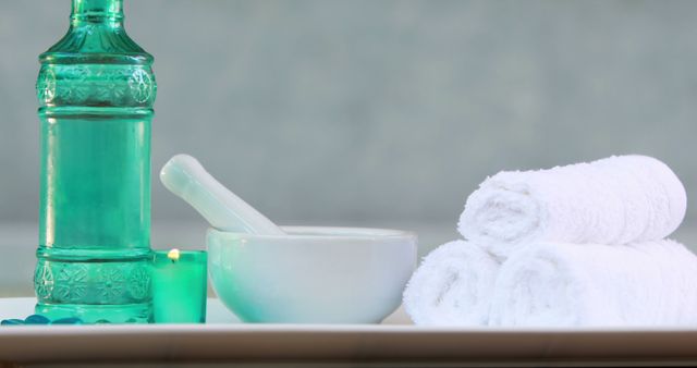 Towels and glass bottle with candle and mortar and pestle at the spa