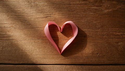 Pink Ribbon Heart on Rustic Wooden Surface Creating Warm Atmosphere