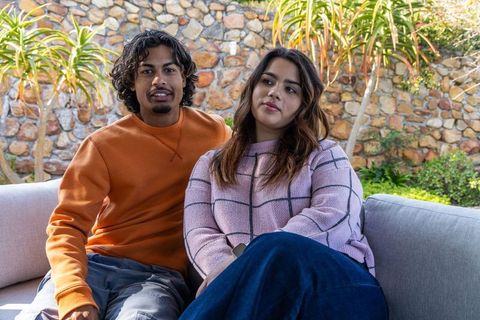 Indian couple sitting on outdoor sofa in backyard patio enjoying relaxed afternoon