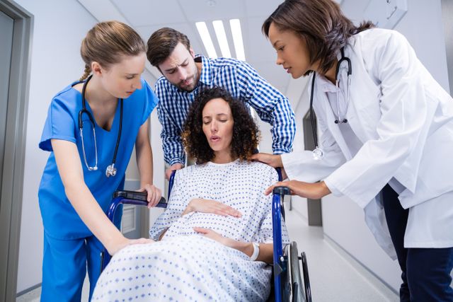 Doctors and man comforting pregnant woman in corridor of hospital