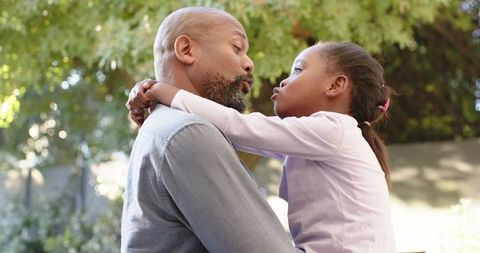 Father-Daughter Embrace Outdoors Under Sunlit Leaves
