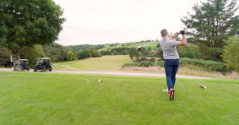 Male Golfer Swinging Club in Picturesque Golf Course Landscape