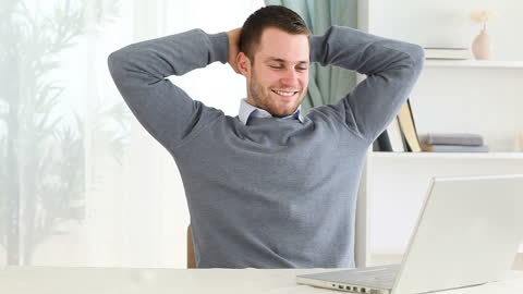 Relaxed Man Enjoying Success at Work with Laptop