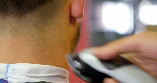 A close-up view of a young Caucasian man getting a haircut, with a barber using clippers on his neck, with copy space. Precision and care are evident in the barber's technique, highlighting the personal grooming experience.