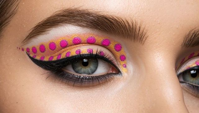 Macro closeup eye makeup featuring gold metallic shadow and magenta polka-dot winged liner