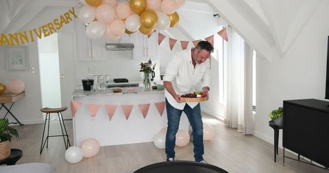 Man celebrating anniversary at home with food preparation and decorations