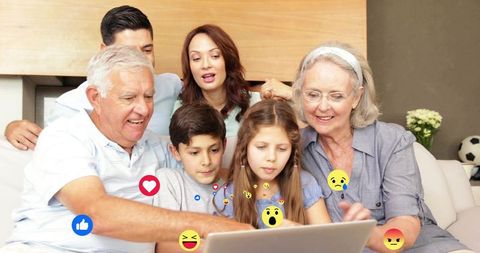 Multigenerational family watching laptop with social media emoji reactions